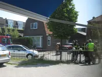 Meester Theo (in het gele hesje) spreekt met de brandweermannen, achter hen is de loods te zien